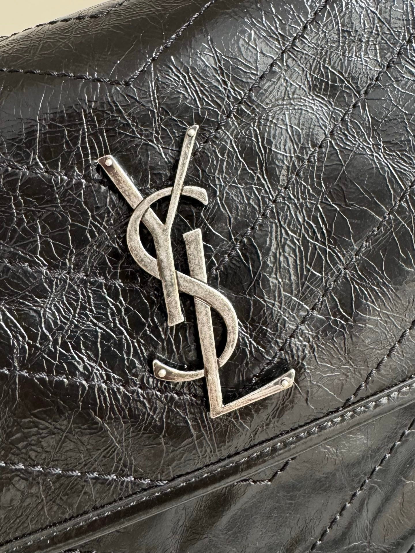 Saint Laurent YSL metal logo on textured black leather flap