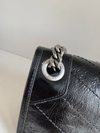 Saint Laurent black leather bag with circular logo plaque on flap