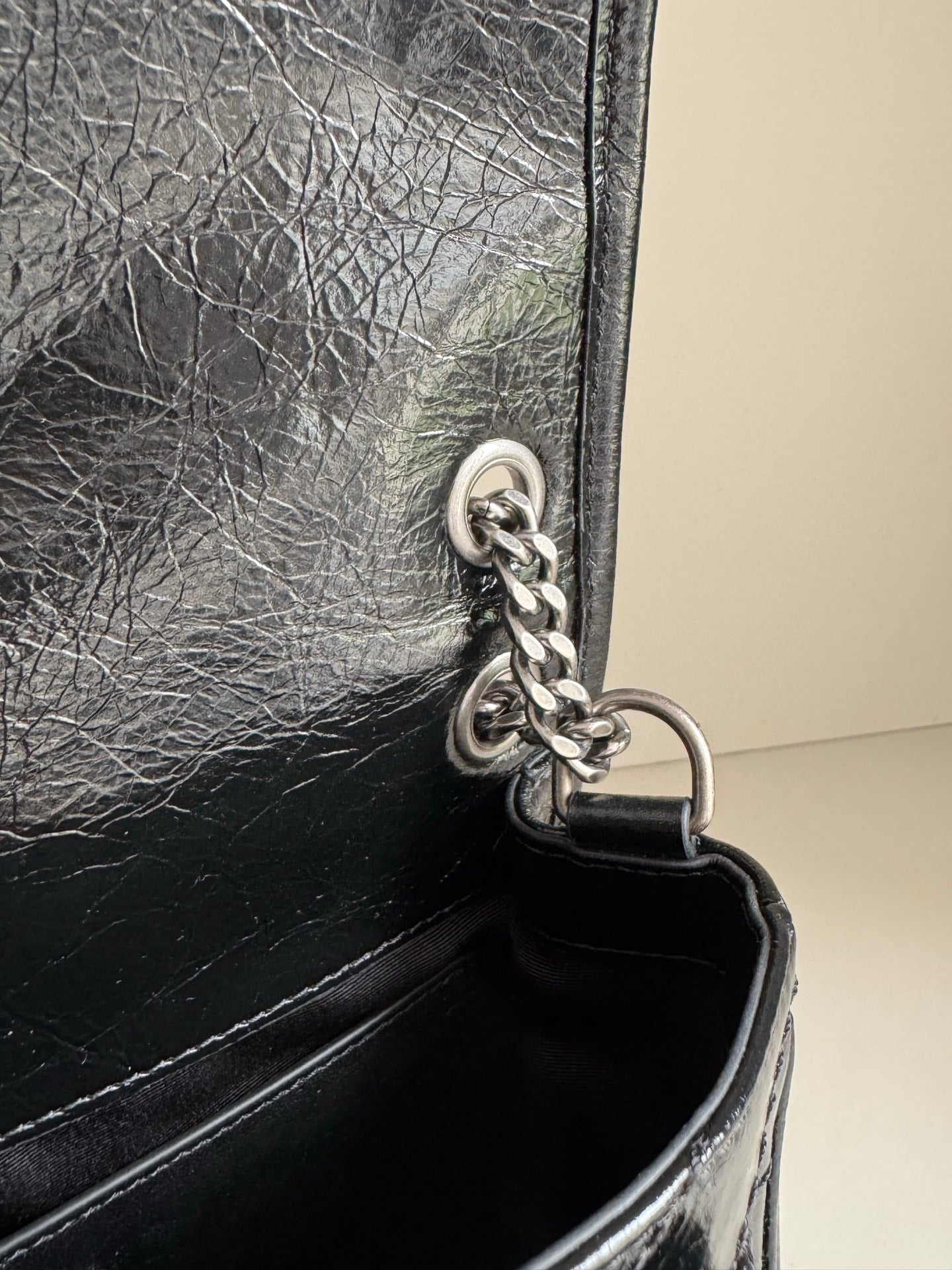YSL dark leather bag corner with chain hardware, metal ring, and stitching