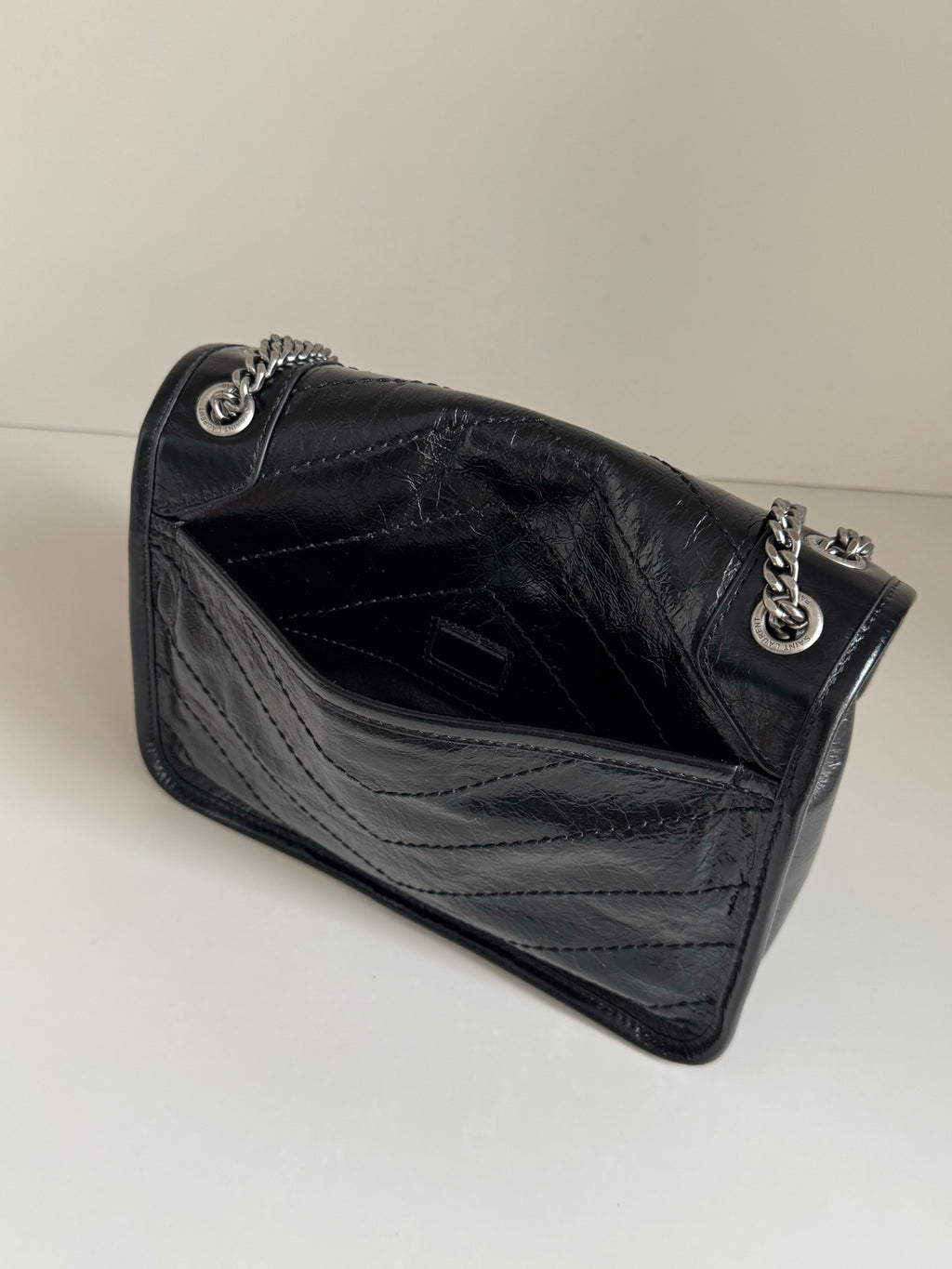 YSL dark leather shoulder bag open showing interior and chain strap hardware