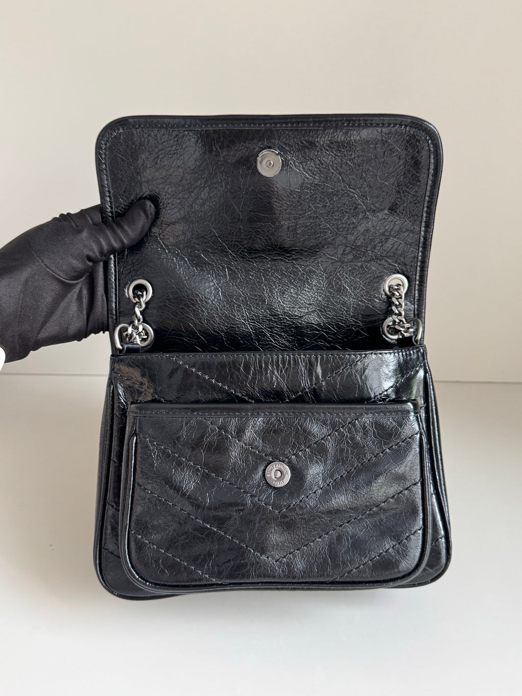 YSL dark leather bag with front patch pocket, snap buttons, and chain pull