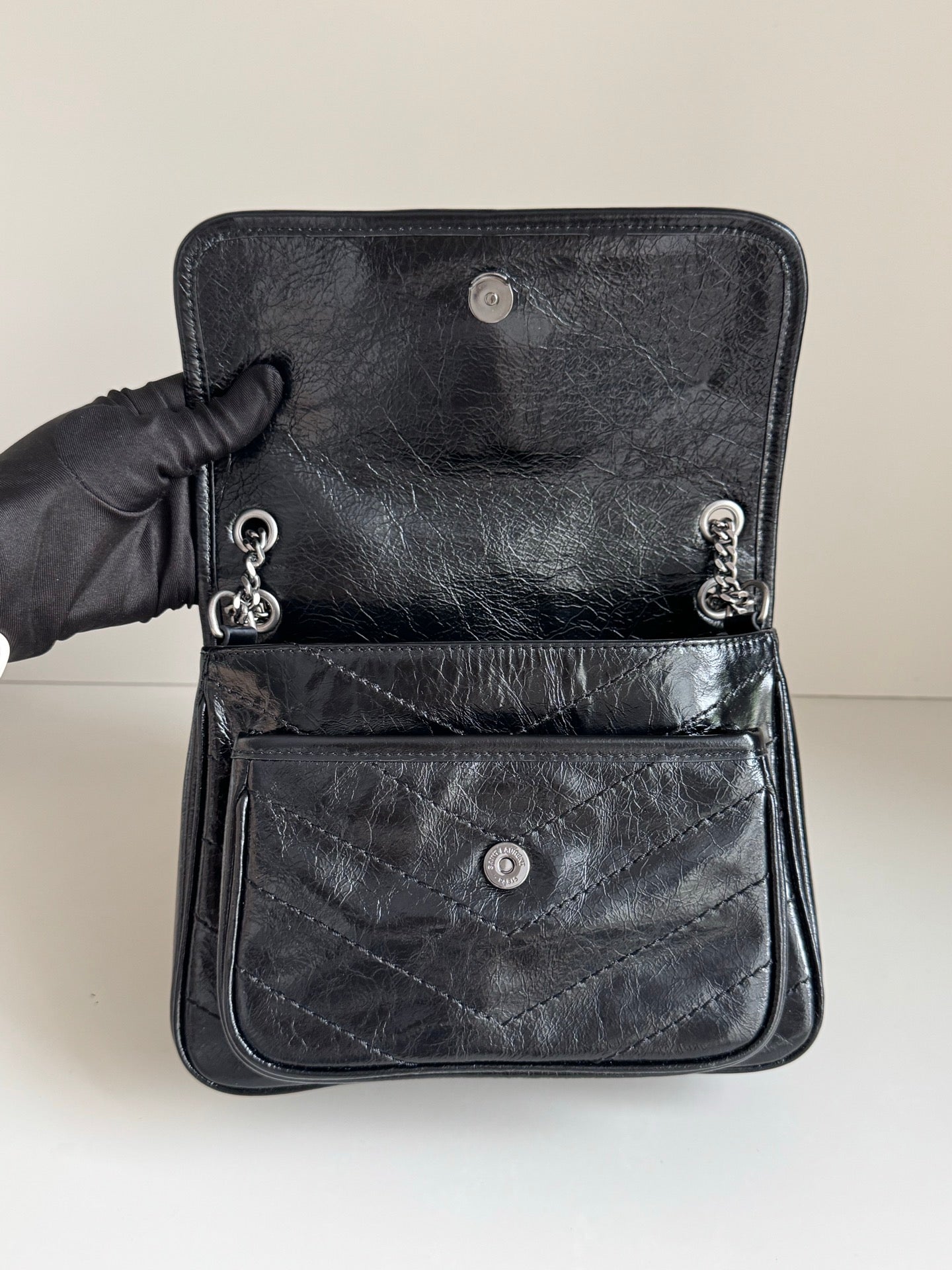 YSL dark leather bag with front patch pocket, snap buttons, and chain pull
