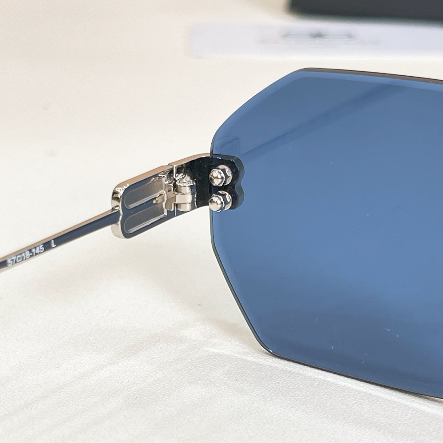 Octagonal sunglasses hinge close-up with blue lens and metal rivets