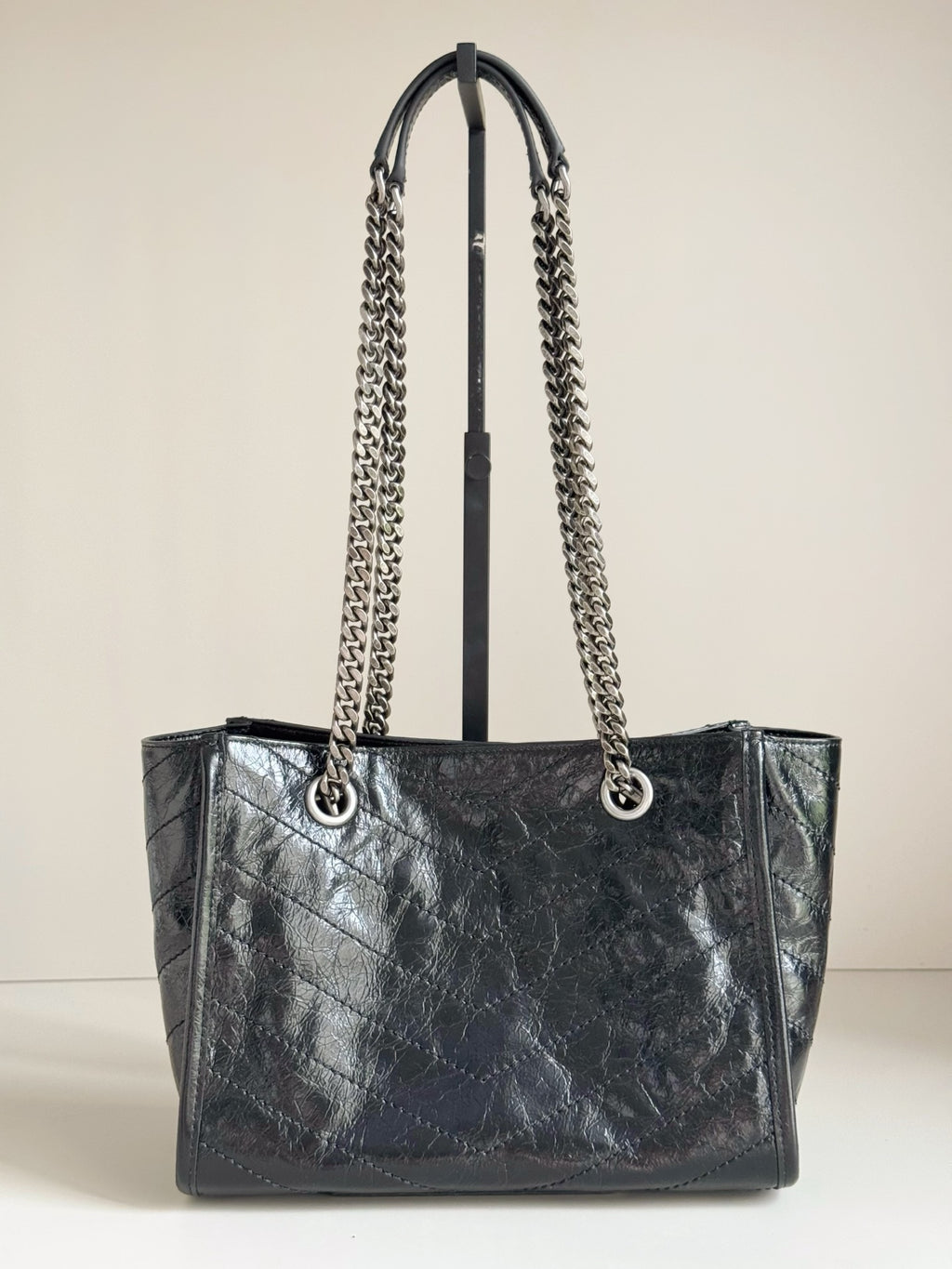 Dark leather tote bag with chain straps and front logo, structured open top