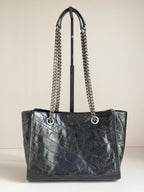 Dark leather tote bag with chain straps and front logo, structured open top