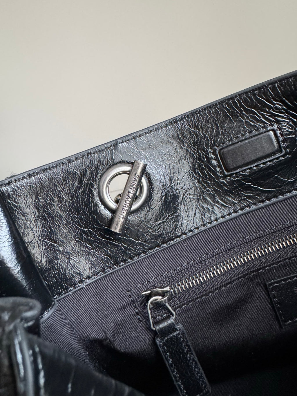 Dark leather tote bag close-up of zipper pocket and chain pull hardware