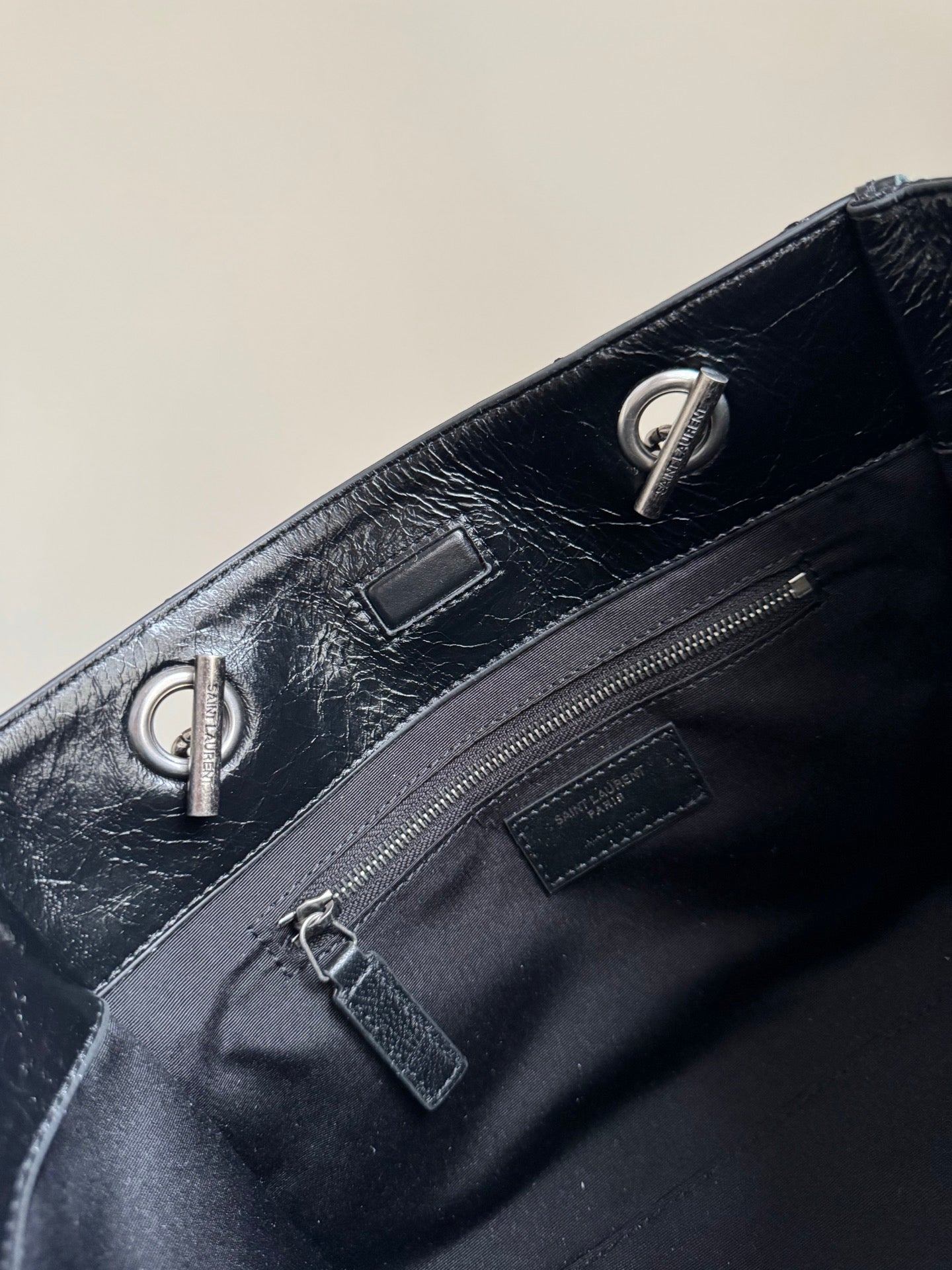 Dark leather tote bag top with chain handle rings and zip pocket hardware