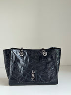 Dark leather tote bag with chain handles and front YSL-style emblem