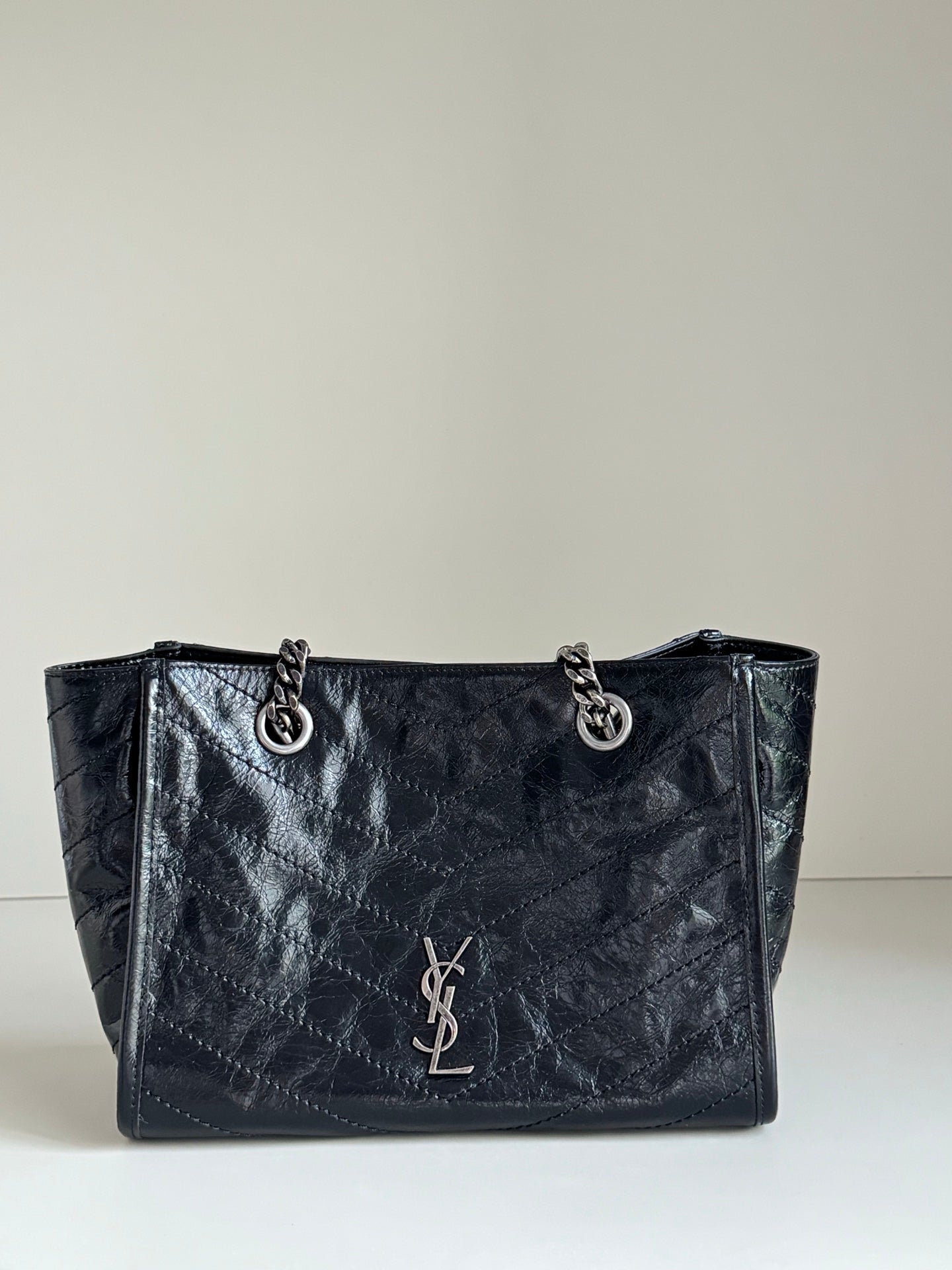 Dark leather tote bag with chain handles and front YSL-style emblem