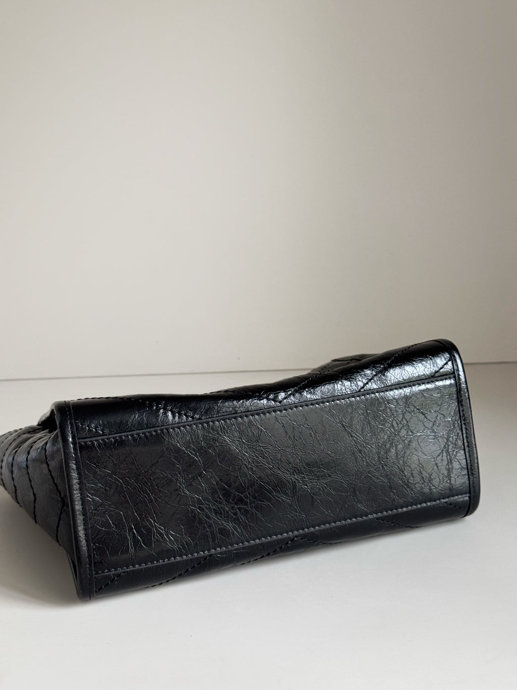 Dark leather tote bag close view of textured surface and stitched corner