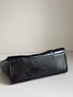 Dark leather tote bag close view of textured surface and stitched corner