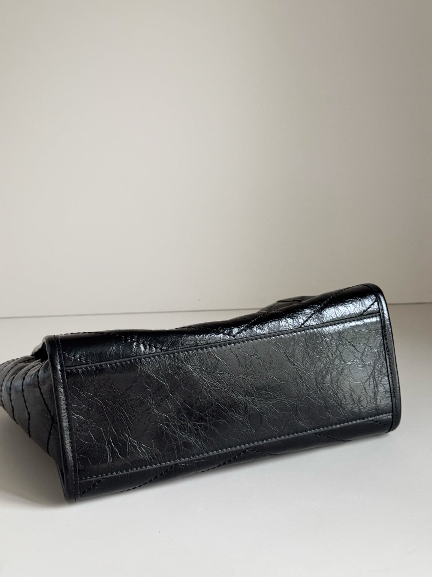 Dark leather tote bag close view of textured surface and stitched corner