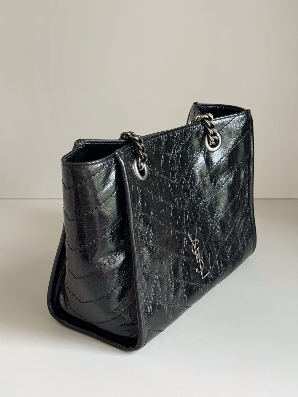 Dark leather tote bag side view with chain strap and inner pocket panel