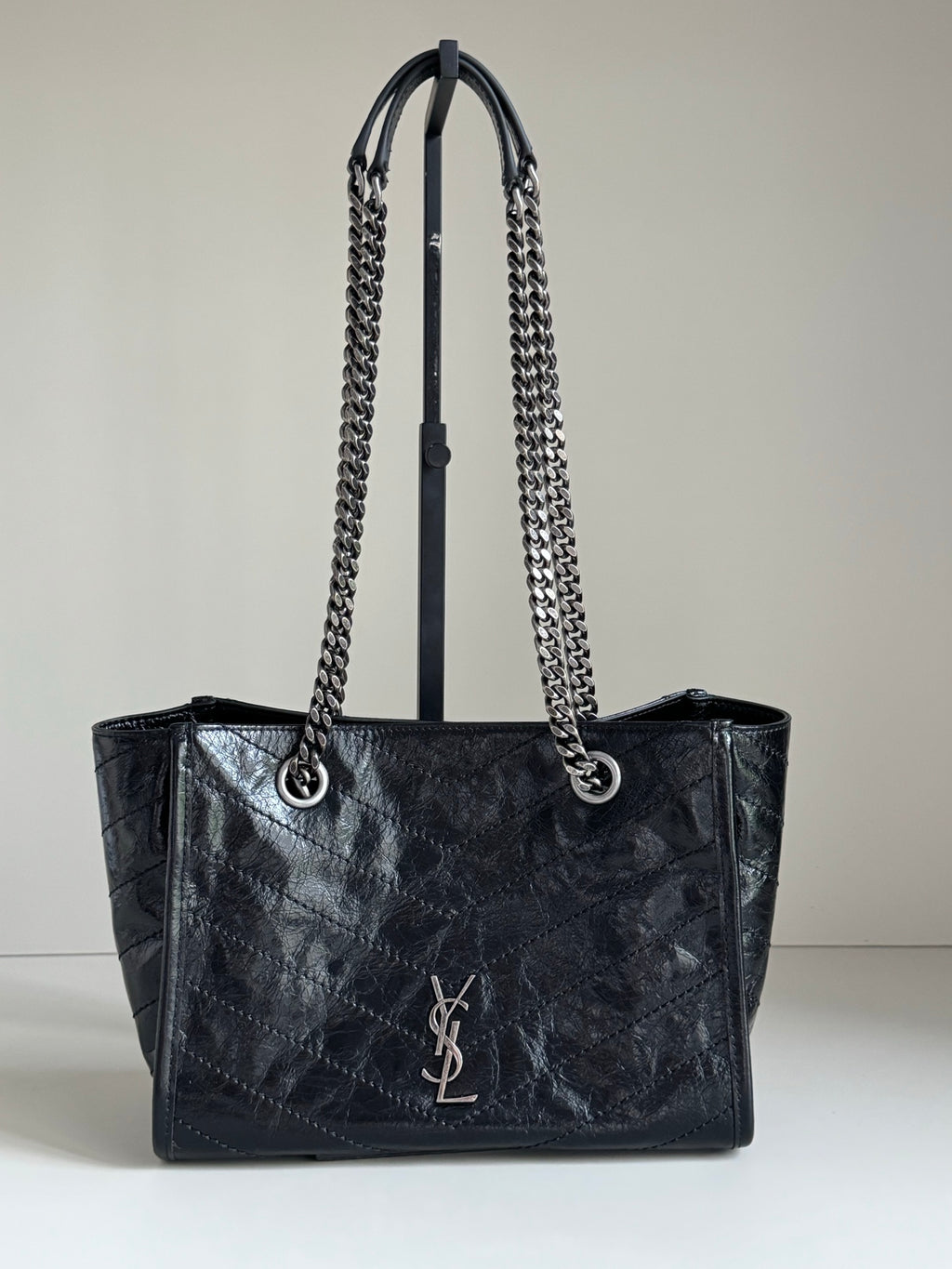 Dark leather tote bag with chain handles and YSL-style logo on the front