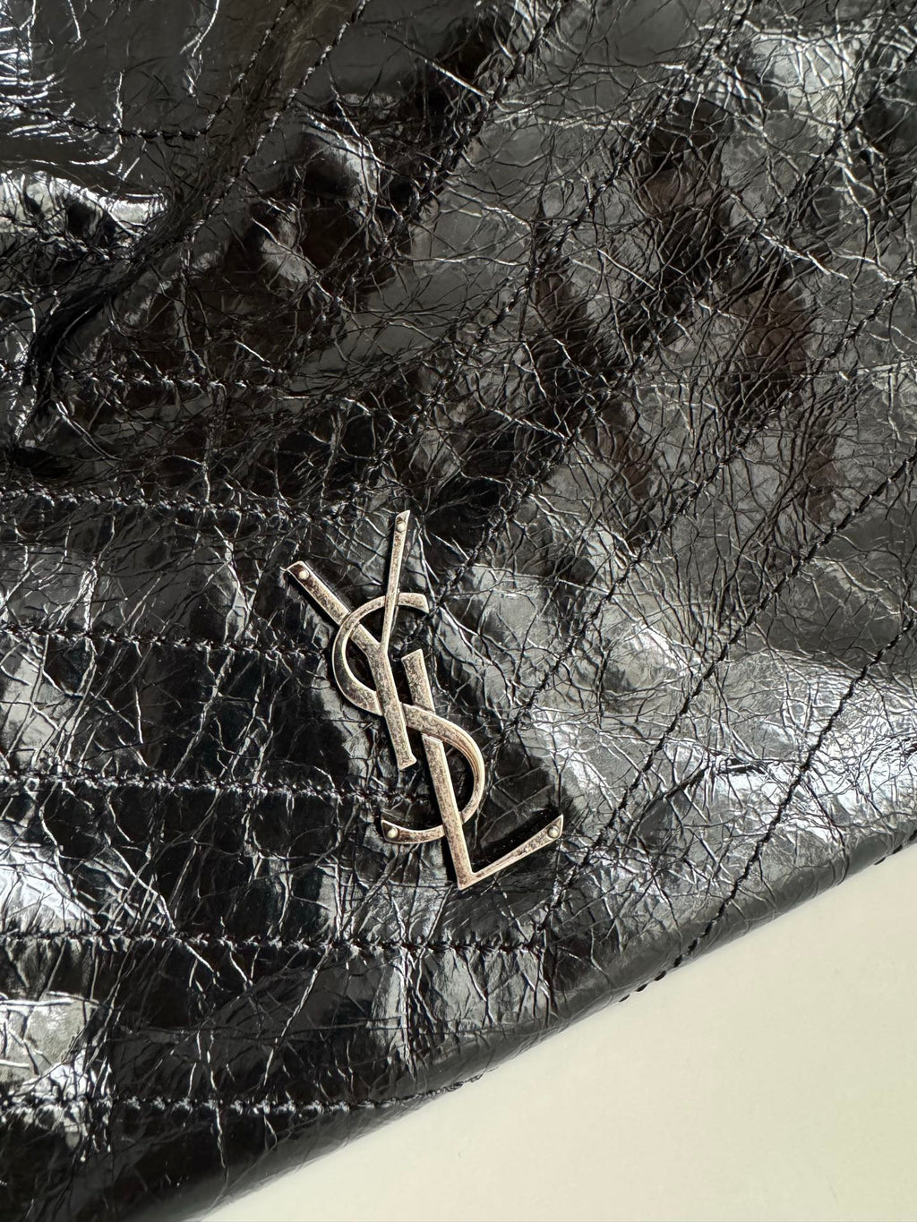 Black leather tote bag corner with YSL metal logo hardware