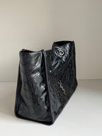Black leather tote bag side view with textured finish and chain strap