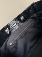 Black leather tote bag close-up of front pocket and zipper pull hardware
