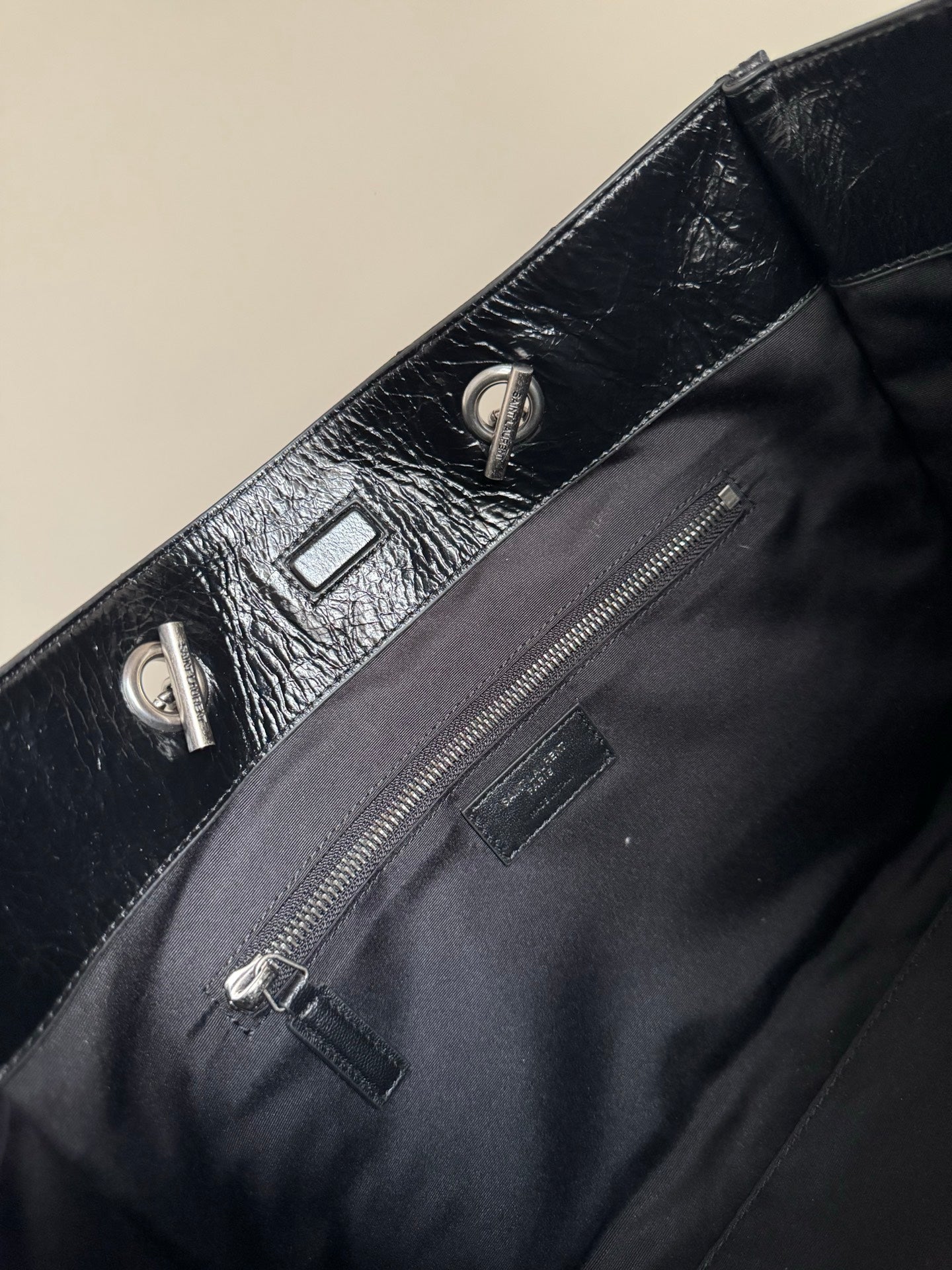 Black leather tote bag close-up of front pocket and zipper pull hardware