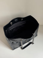 Black leather tote bag interior with chain strap and top edge trim