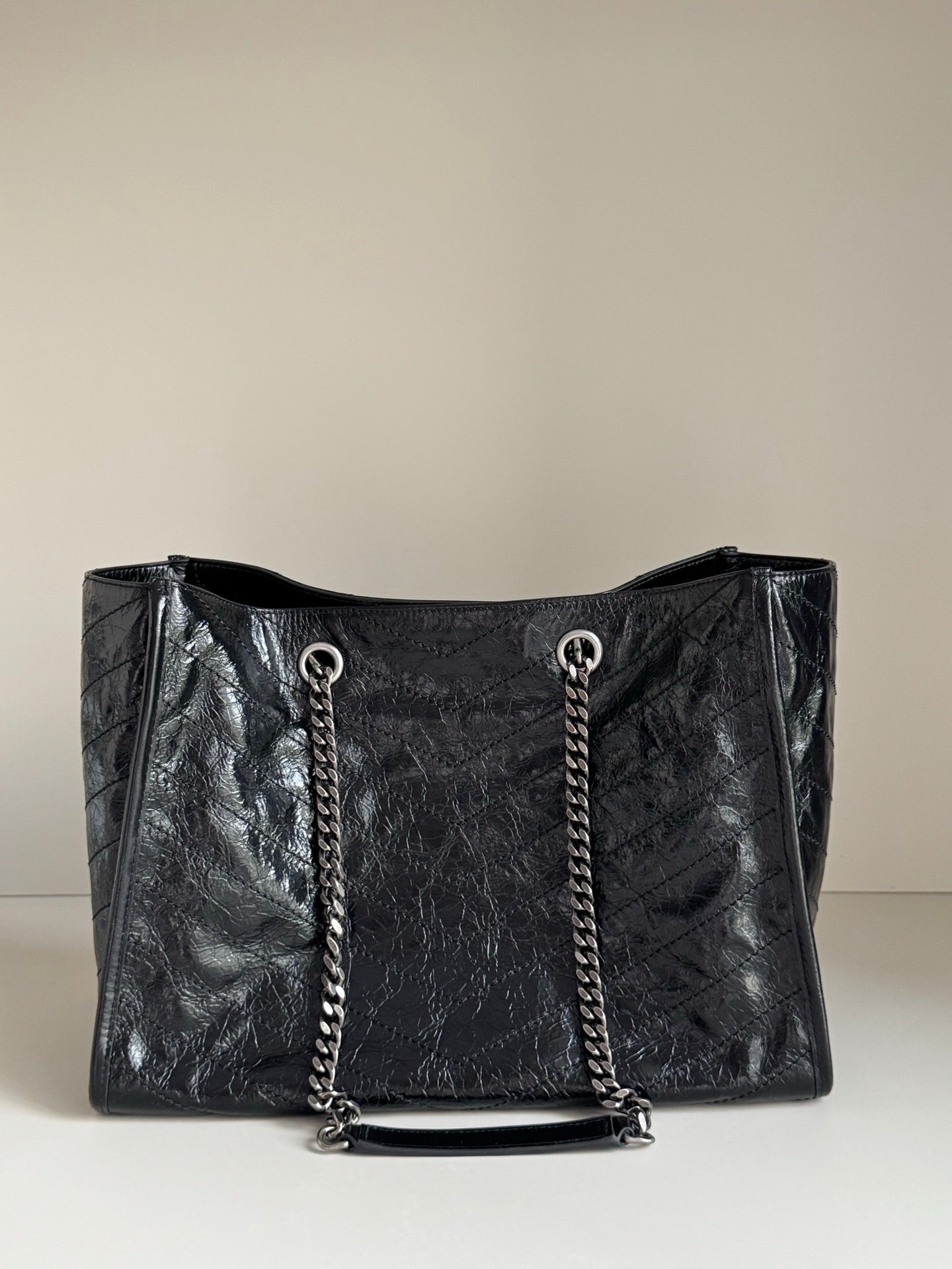 Black leather tote bag front view with chain handles and top opening