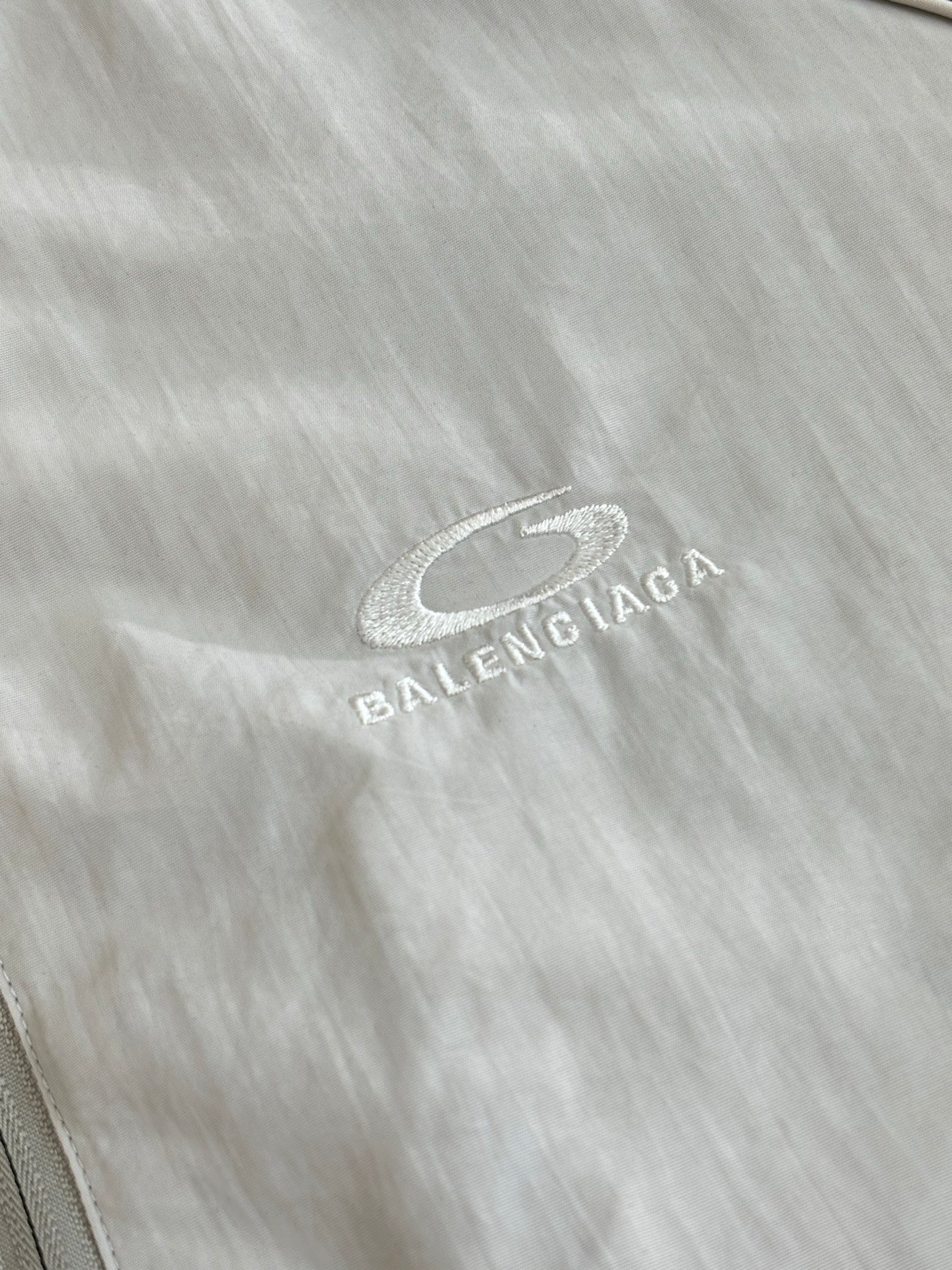 Balenciaga logo patch on light fabric, oval mark with text