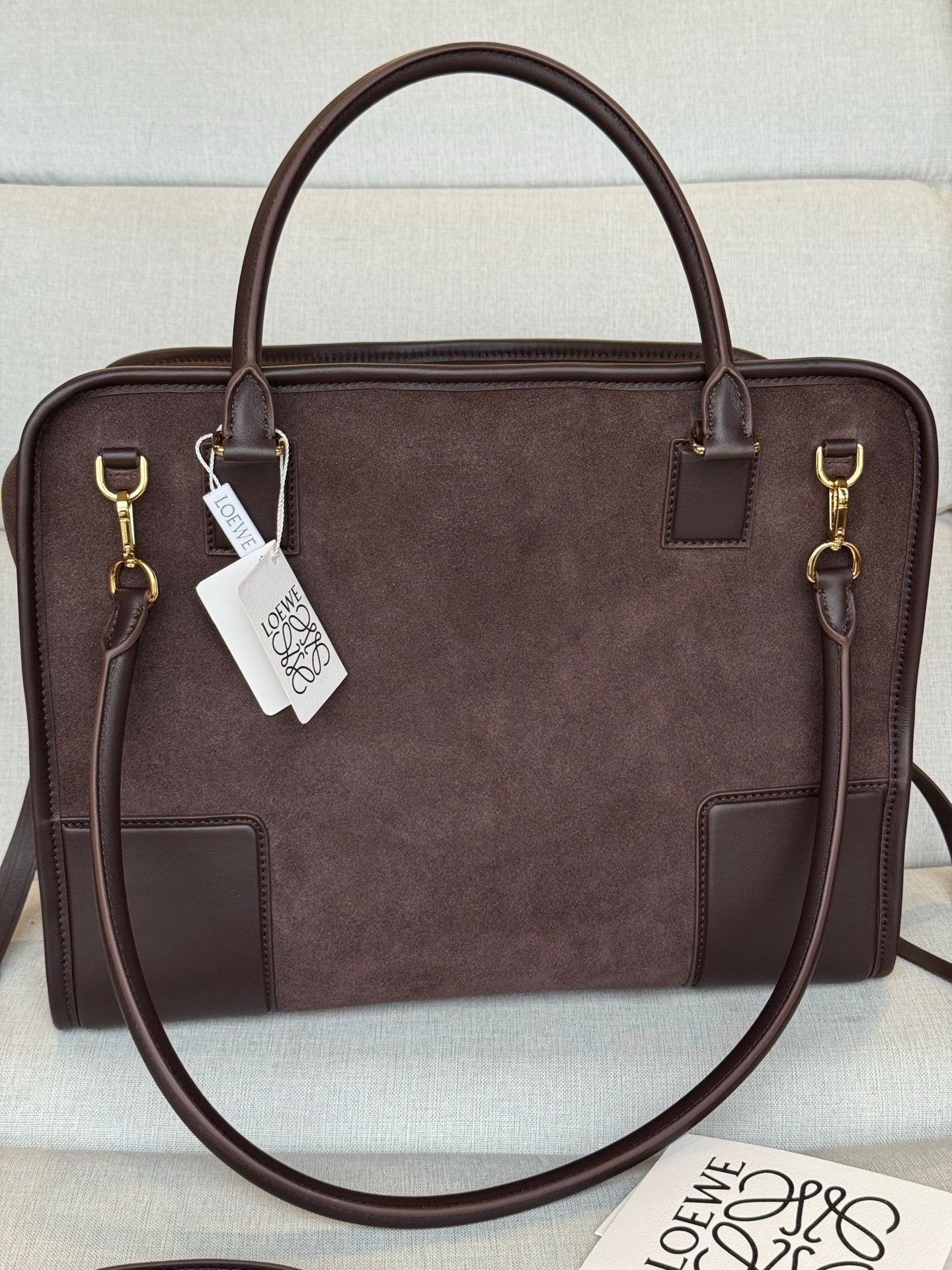 Loewe dark brown leather handbag with structured shape, top handles, and hanging tags