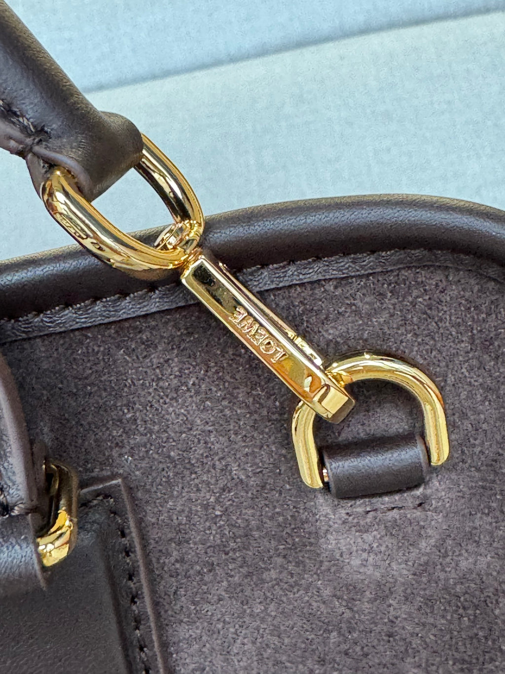 Loewe gold-tone hardware close-up on dark brown leather strap and bag handle