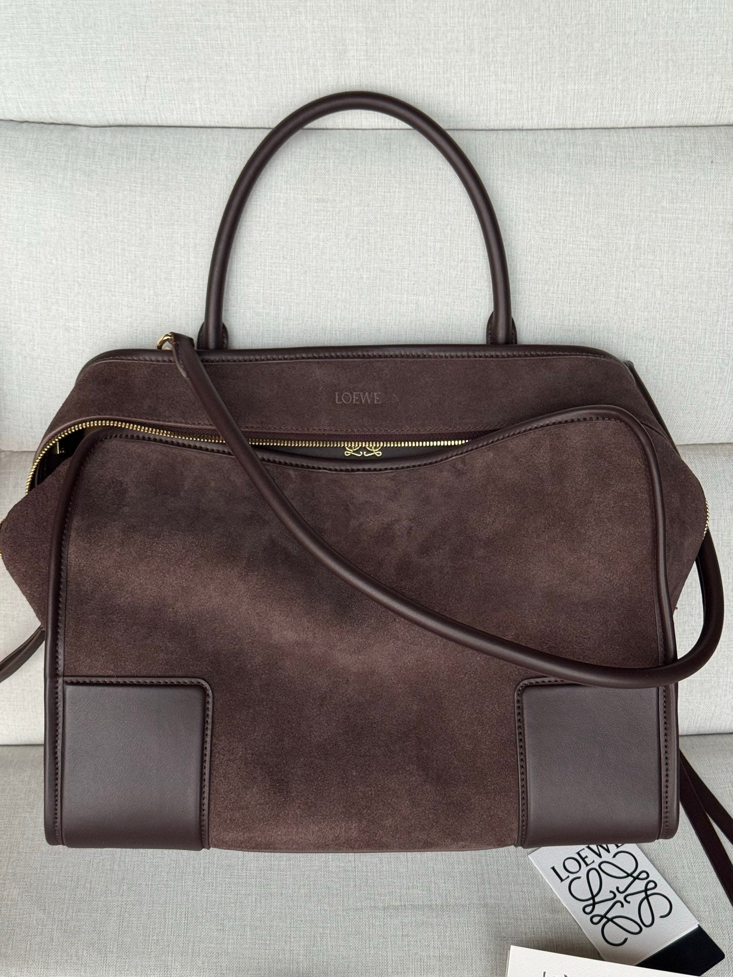 Loewe brown leather handbag with top handles, side zip pocket, and crossbody strap