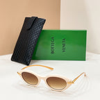 Cream sunglasses with brown lenses and gold-toned accents, beside textured black case.