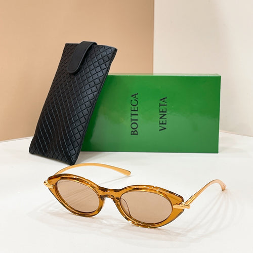 Amber sunglasses with amber lenses and gold-toned frame accents, beside textured black case.