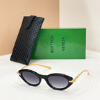 Black sunglasses with dark lenses and gold details, beside textured black case.
