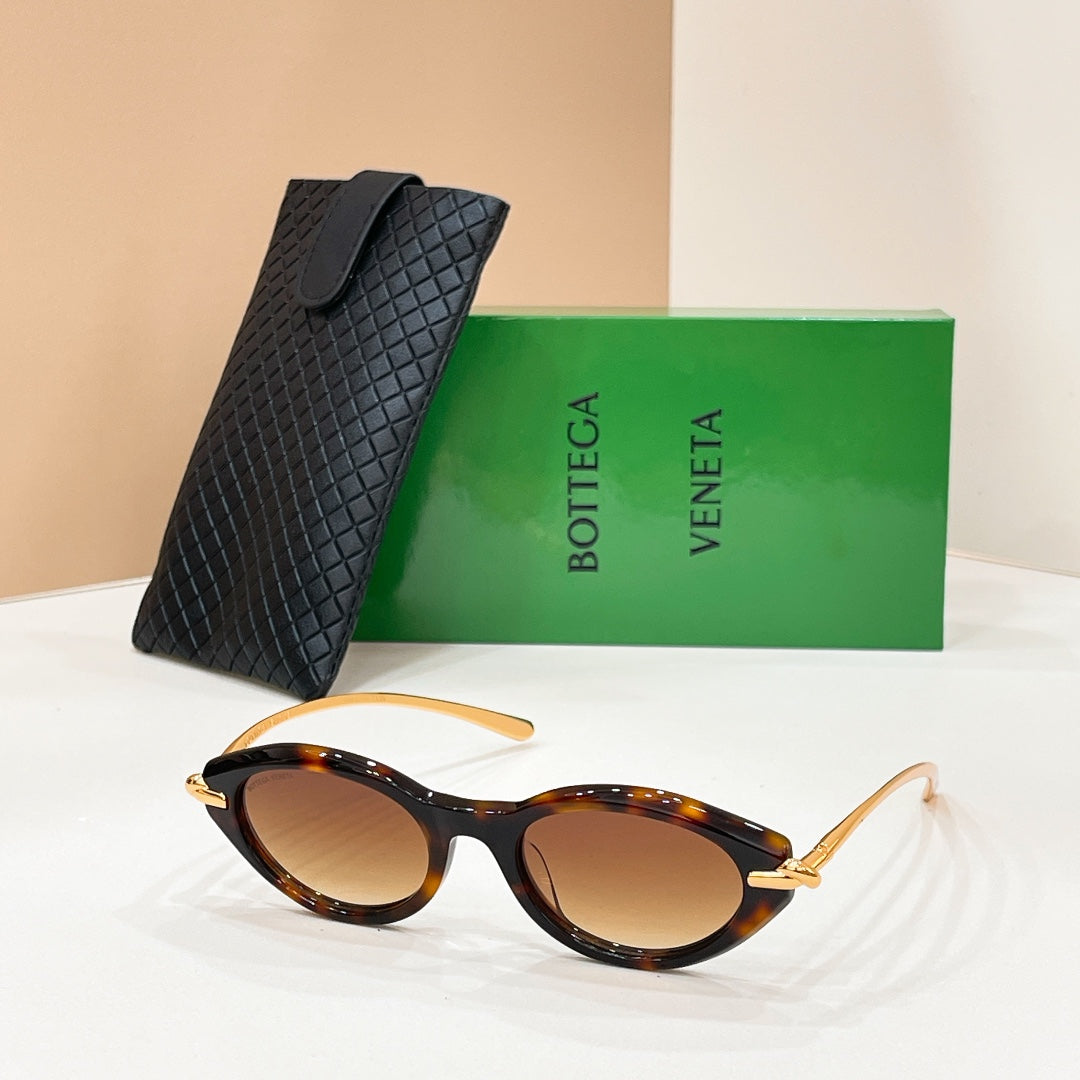 Tortoiseshell sunglasses with brown lenses and gold details, beside textured black case.