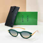 Green sunglasses with tinted lenses and gold details, beside textured black case.