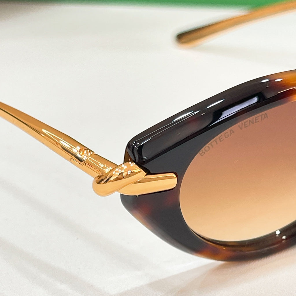 Tortoiseshell sunglasses close-up with gold hinge and brown-tinted lens.