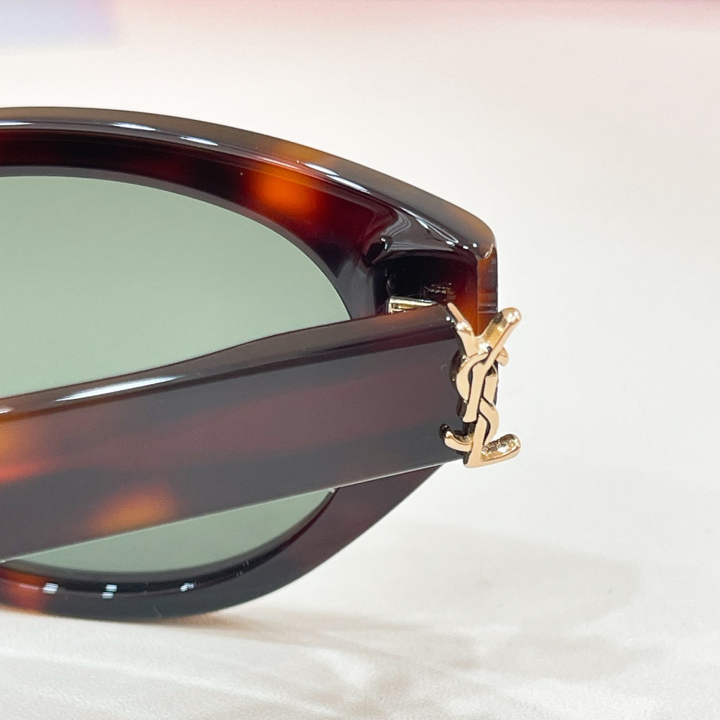 Tortoiseshell sunglasses close-up: glossy lenses with gold-tone charm on the side