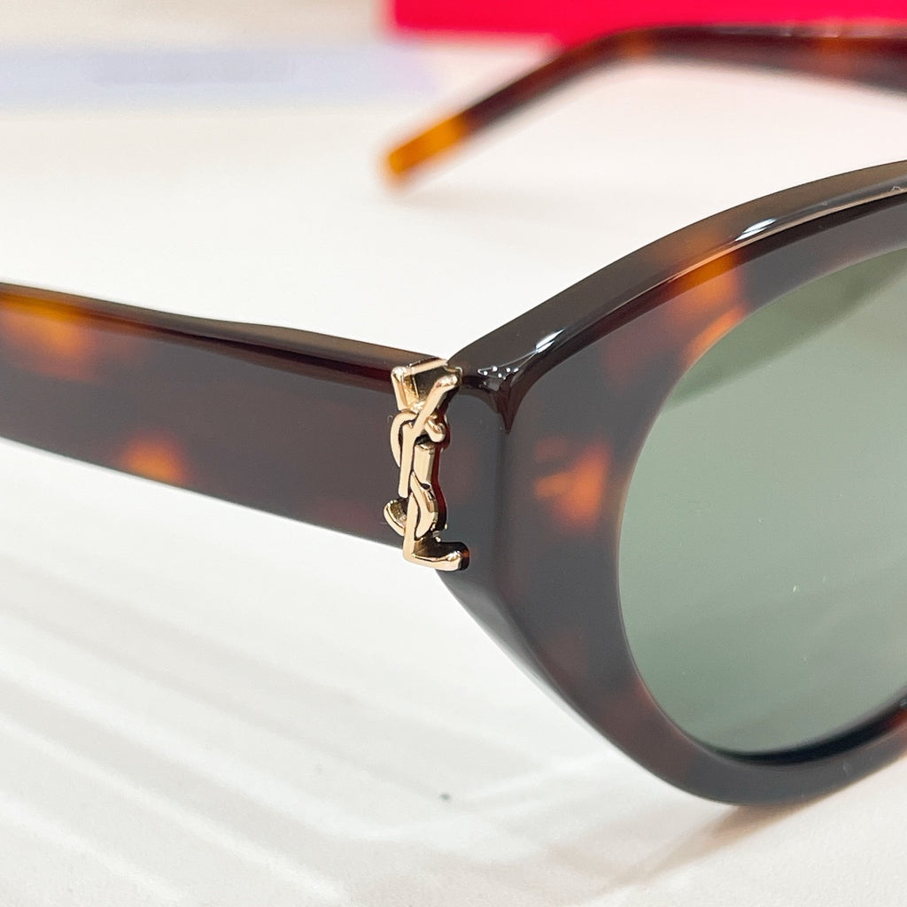 Tortoiseshell sunglasses side close-up with gold-tone charm detail and tinted lens