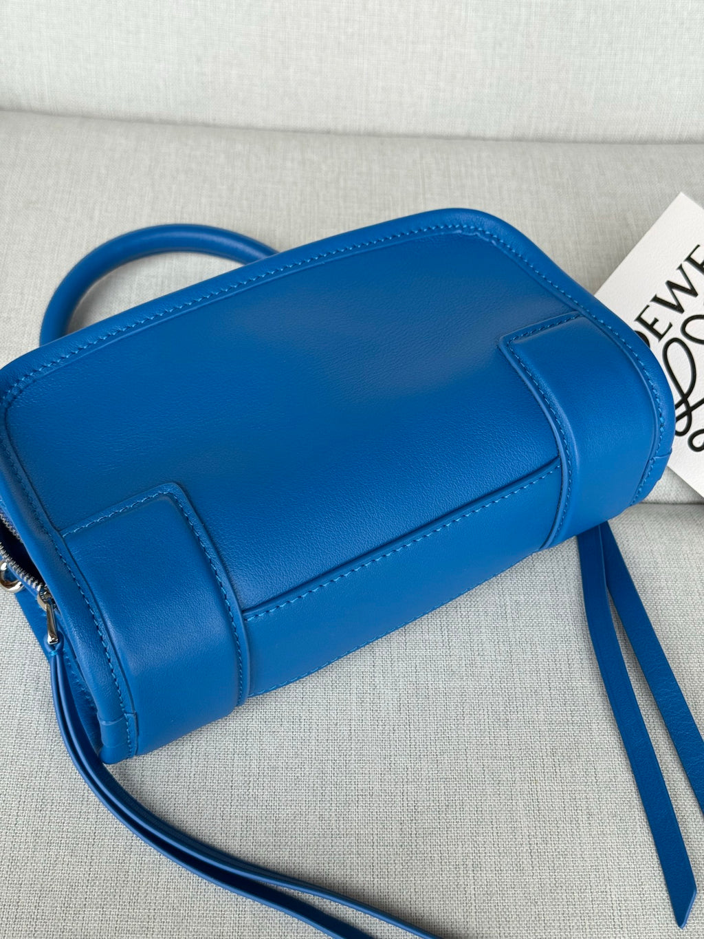 Blue leather mini cylinder bag with structured front panel and adjustable shoulder strap
