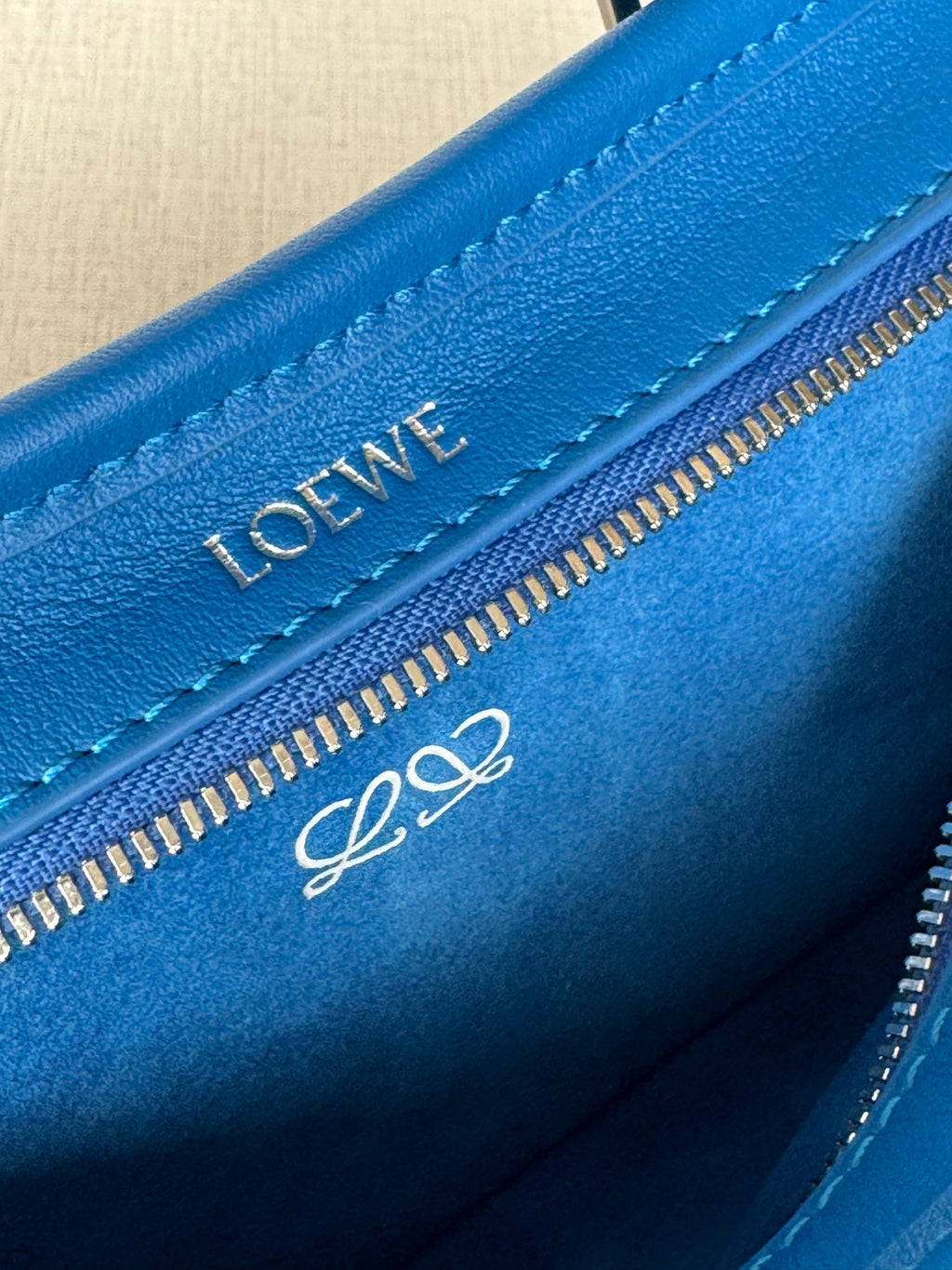 Blue leather bag interior edge with Loewe logo on zipper strip