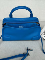 Blue leather handbag with top handle, front logo detail, and two zip compartments