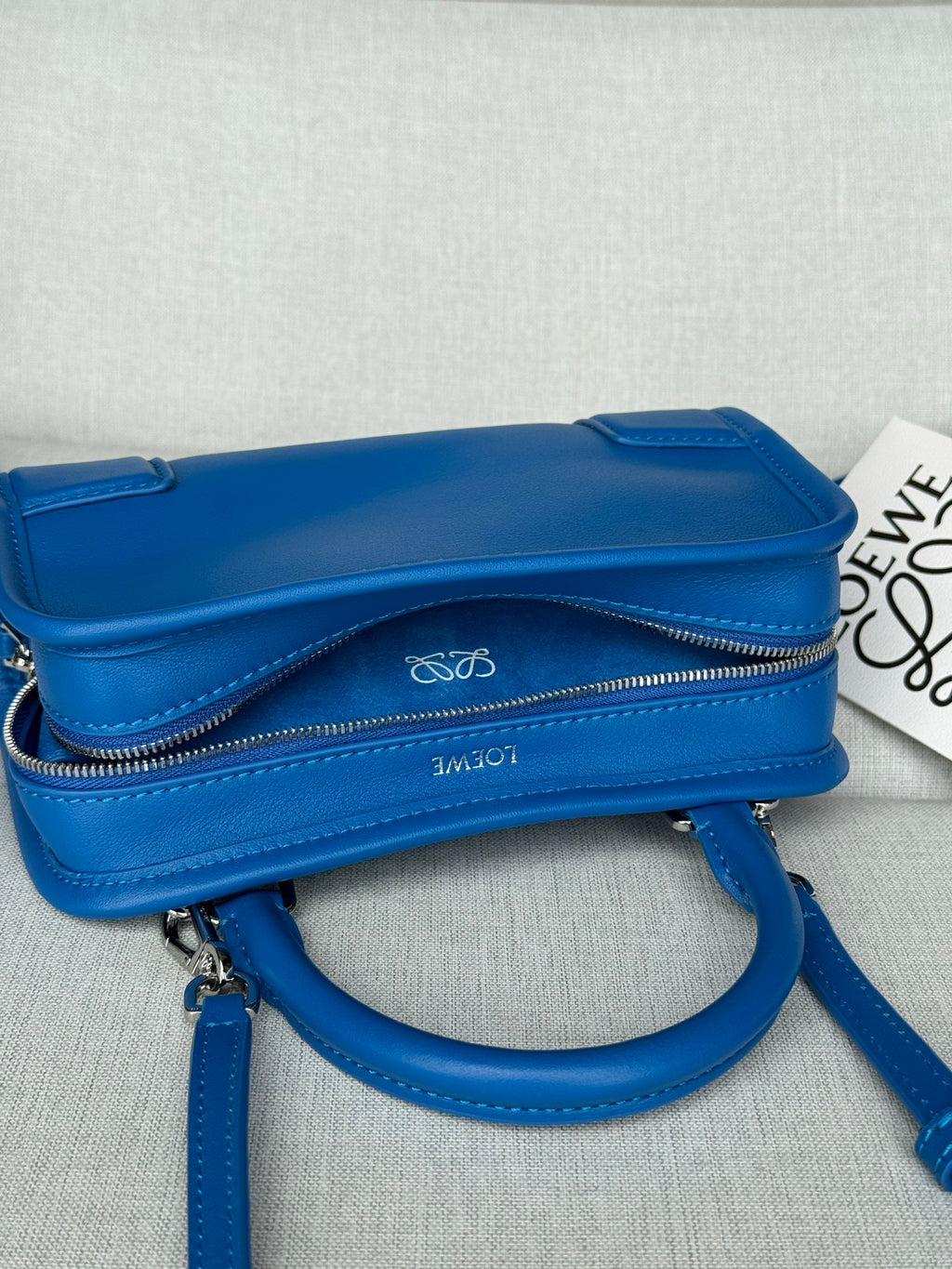 Blue leather crossbody bag with flap top, zip closure, and long shoulder strap