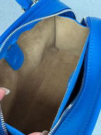 Opened blue leather bag showing beige suede-like interior lining and zipper track
