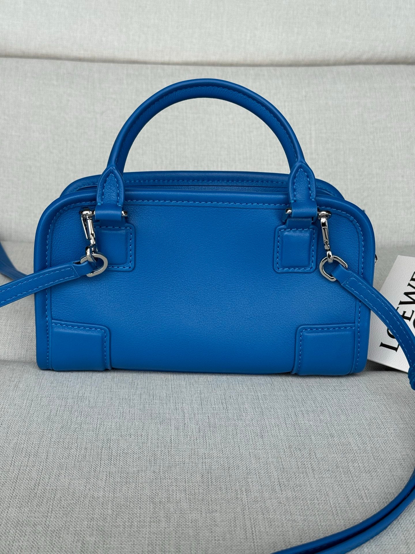 Blue leather top-handle bag with short straps, zipper closure, and crossbody strap