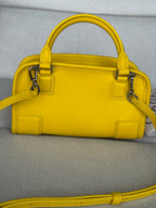 Yellow leather structured bag with top handles, front flap, and crossbody strap