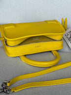 Yellow leather mini shoulder bag with front flap, long strap, and metal hardware