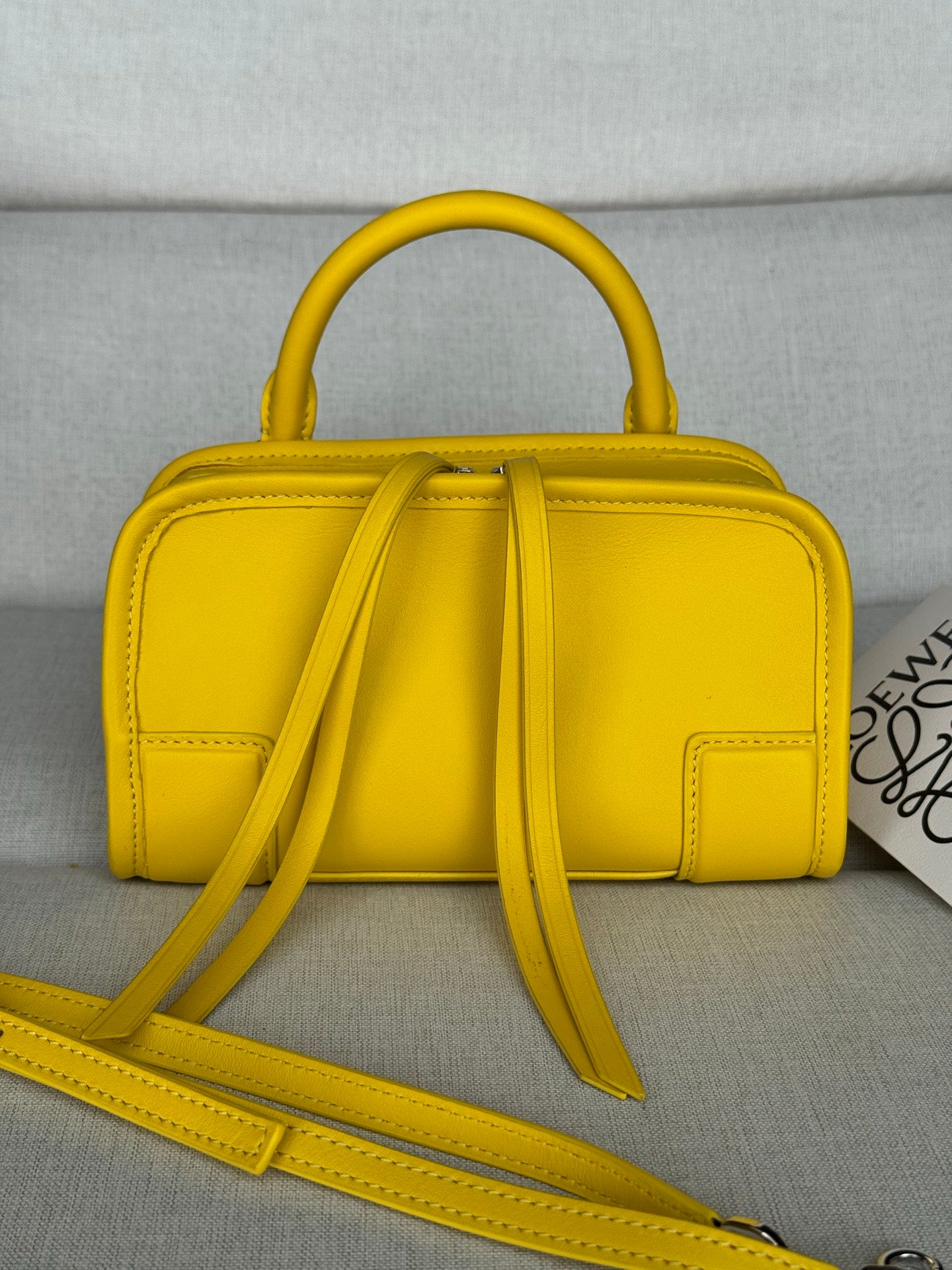 Yellow leather top-handle bag with bow-like tassel detail and crossbody strap