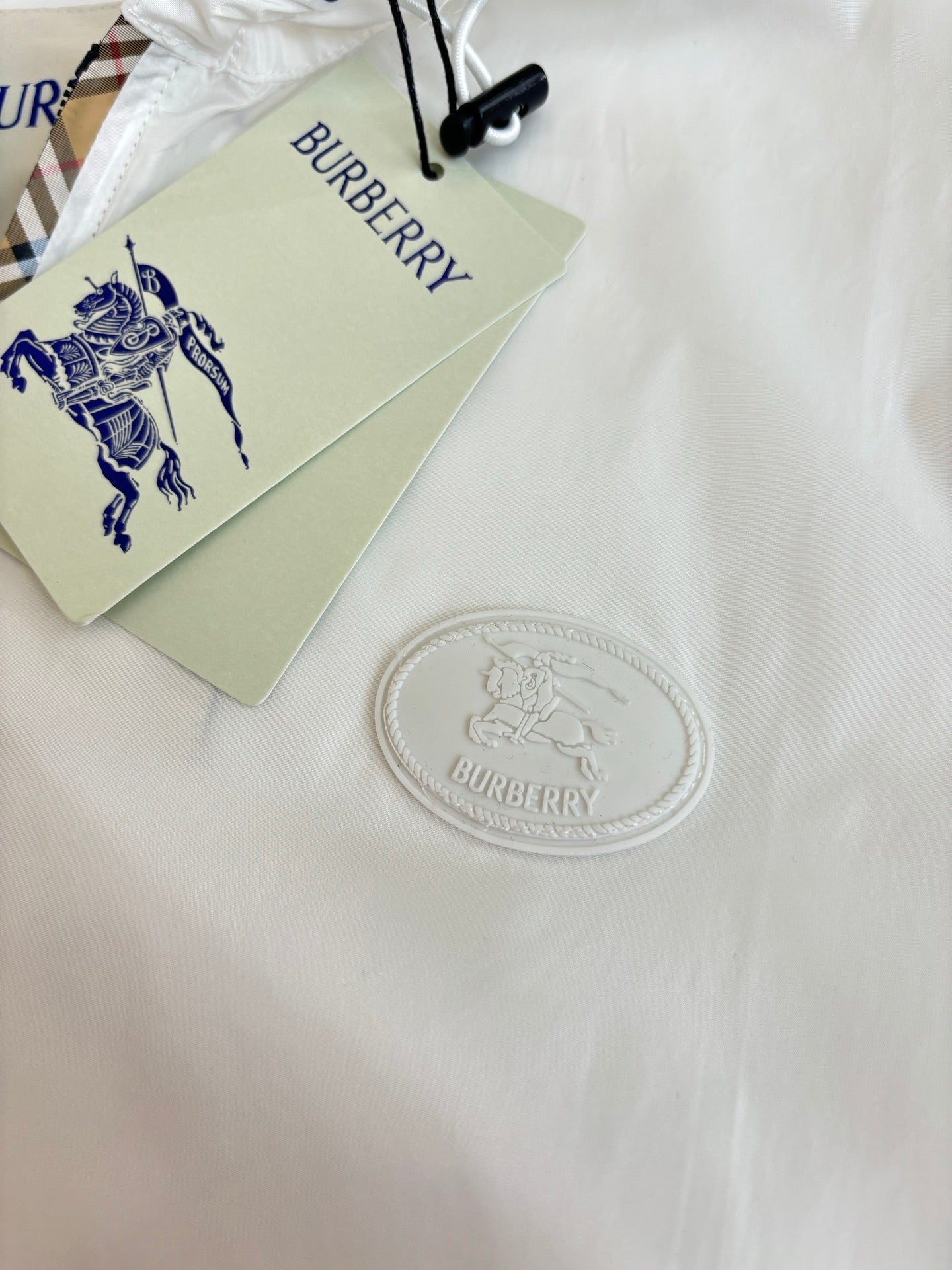 Burberry tags and embossed logo coin on white fabric