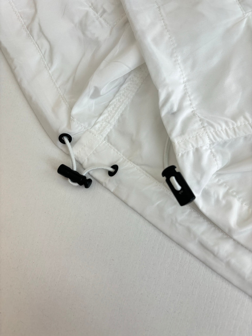 White jacket hood with black drawstring and plastic toggles