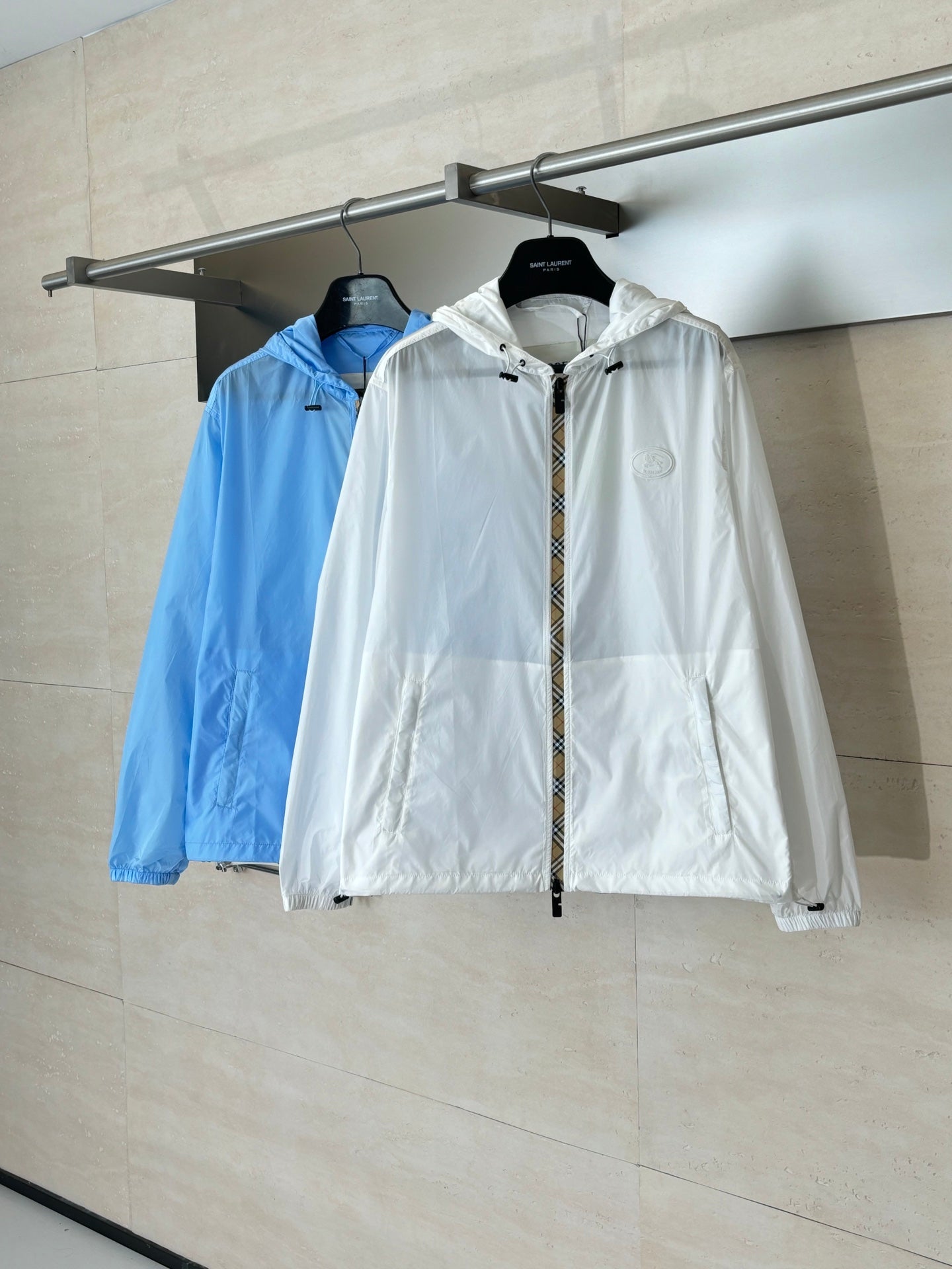 Burberry hooded jackets on hangers: white jacket in front, blue behind