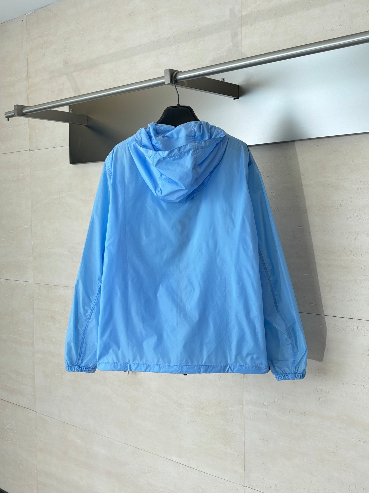 Blue hooded jacket, back view with gathered hood and zipper