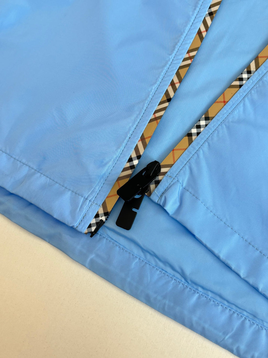 Blue jacket zip placket detail with black zipper tape and striped trim